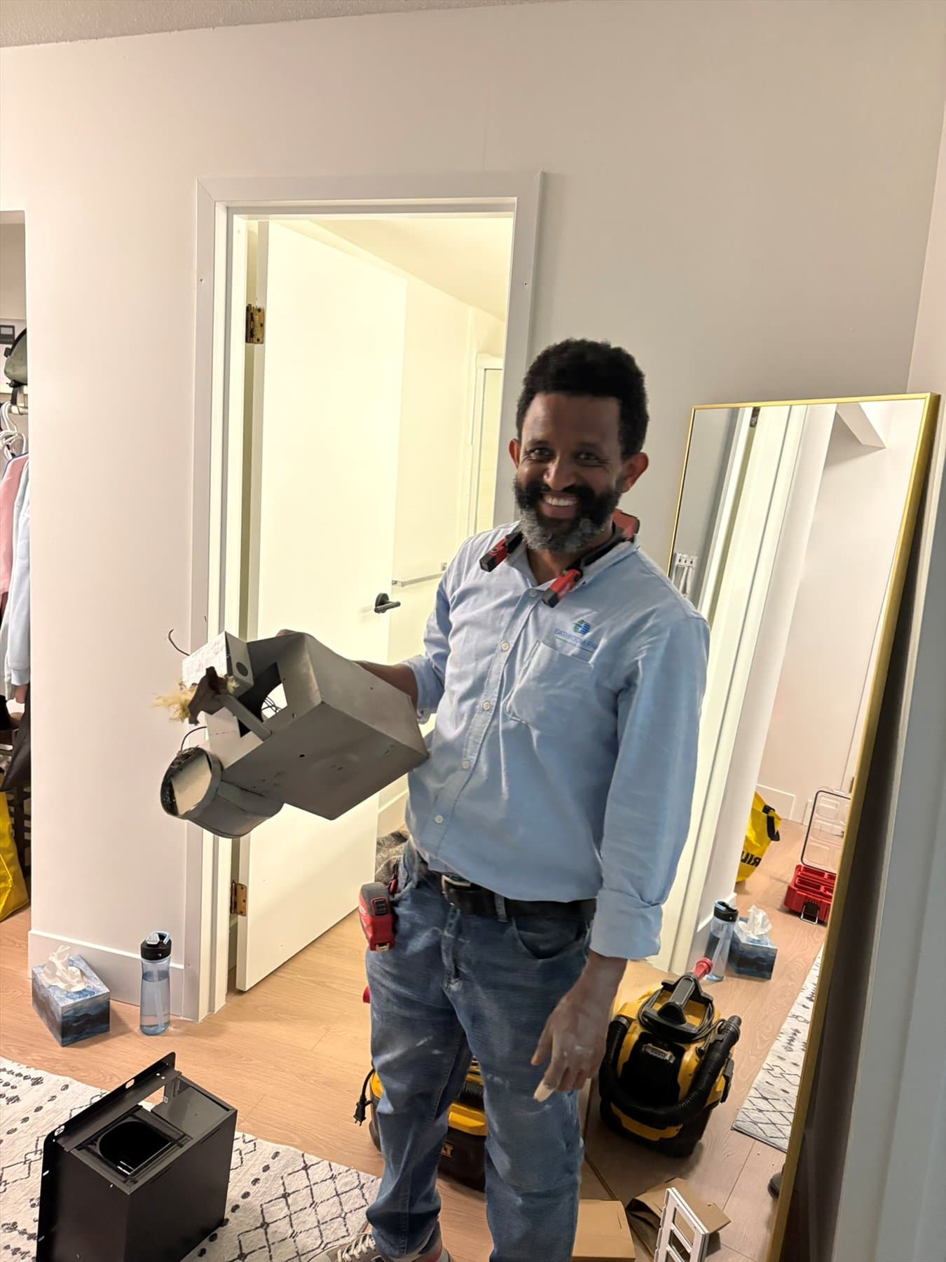 Bathroom Fan Pros installer holding the removed fan in East Vancouver