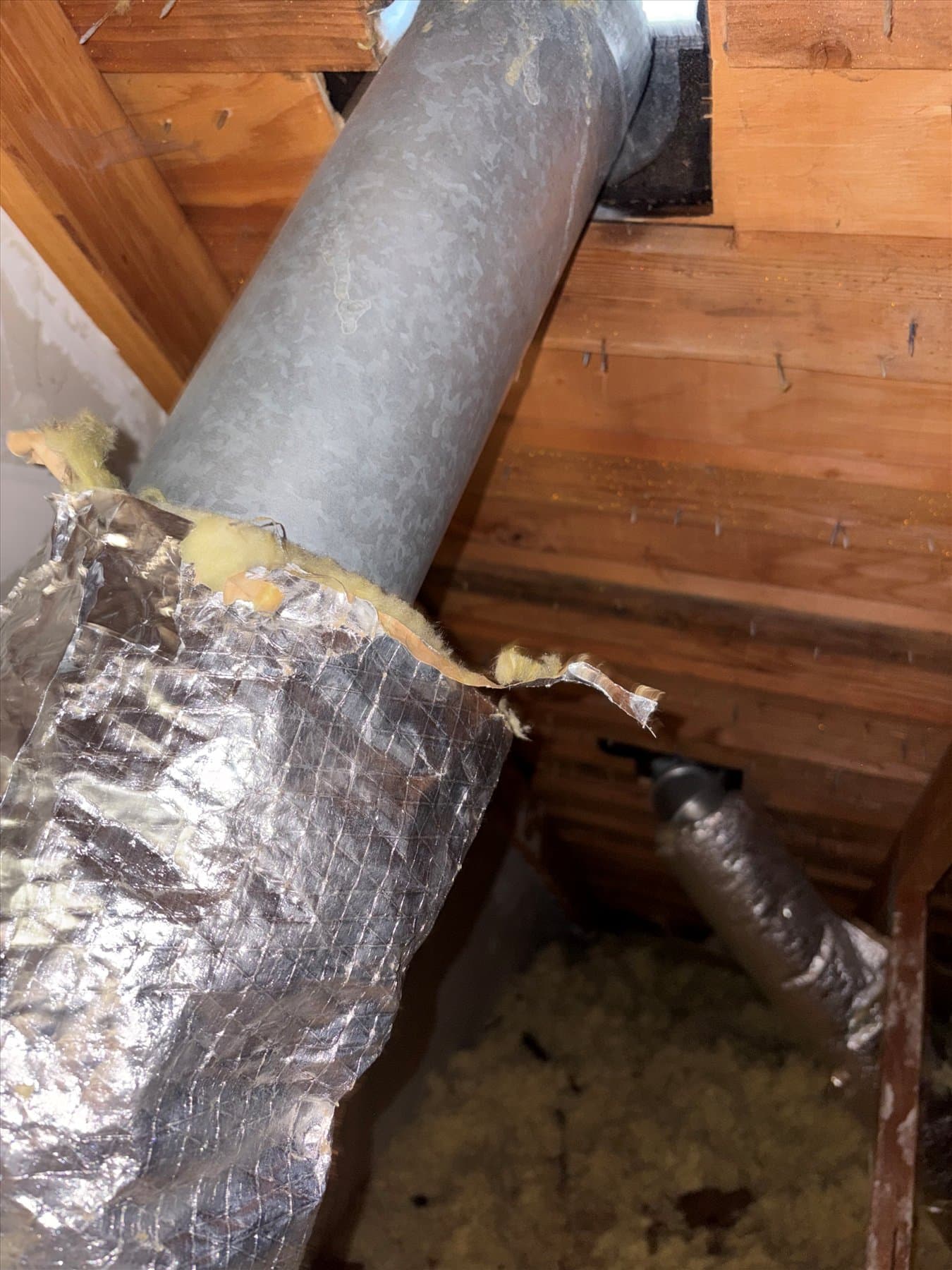 Small bathroom exhaust duct beside ceiling insulation