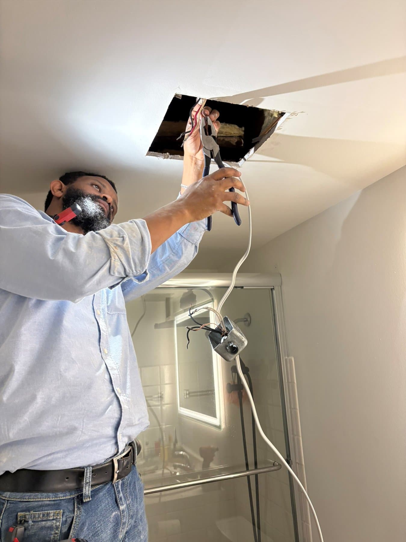 Installer removing the old bathroom fan housing