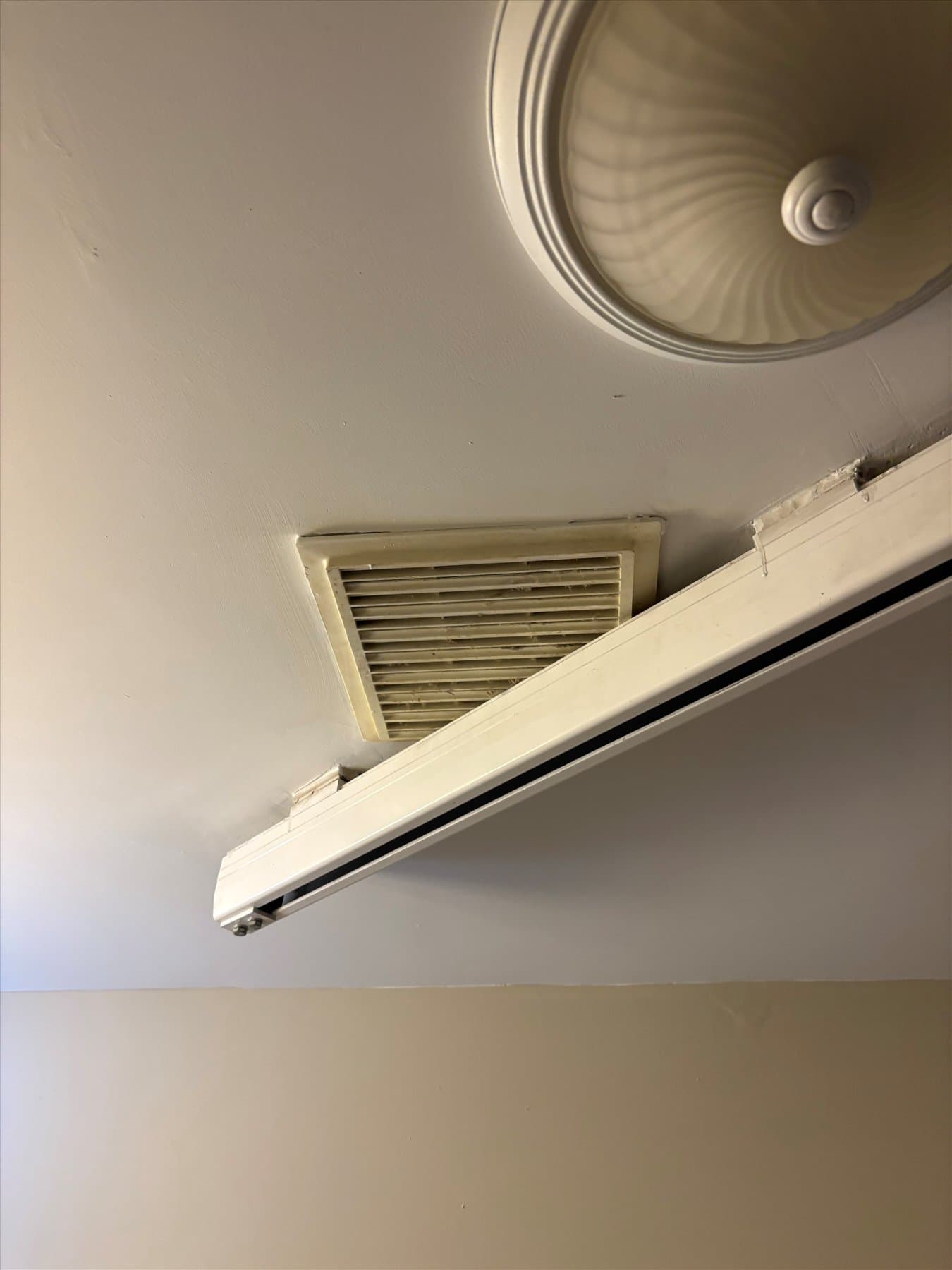 Old bathroom fan grille near the accessibility rail